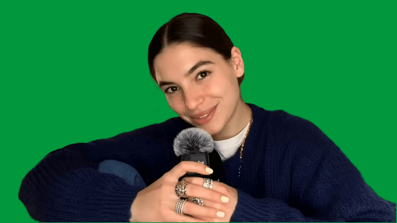 Presenter holding a microphone in front of a green screen
